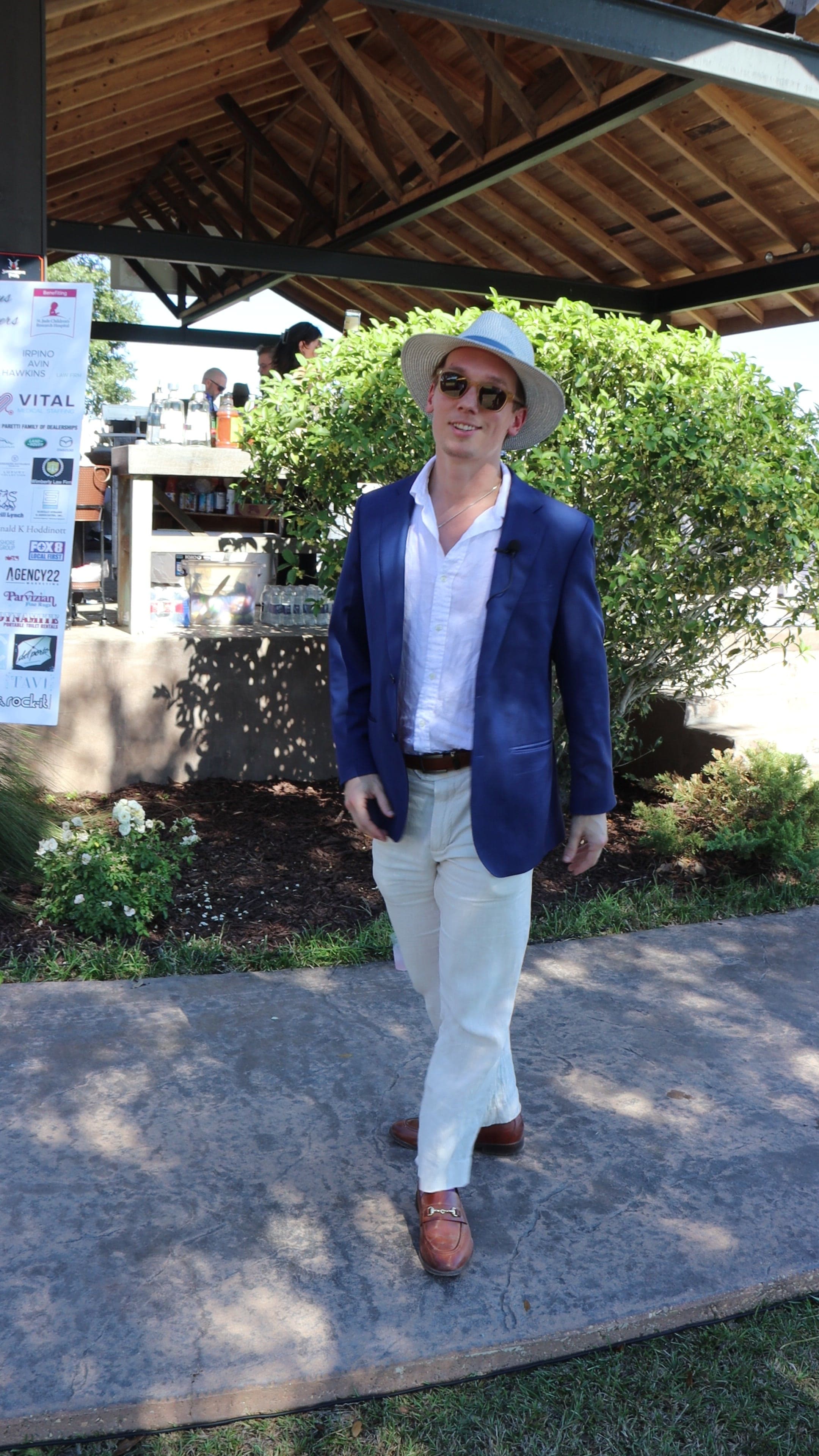 Garrett Shearman in a straw hat and blazer beneath a pavilion at a polo event