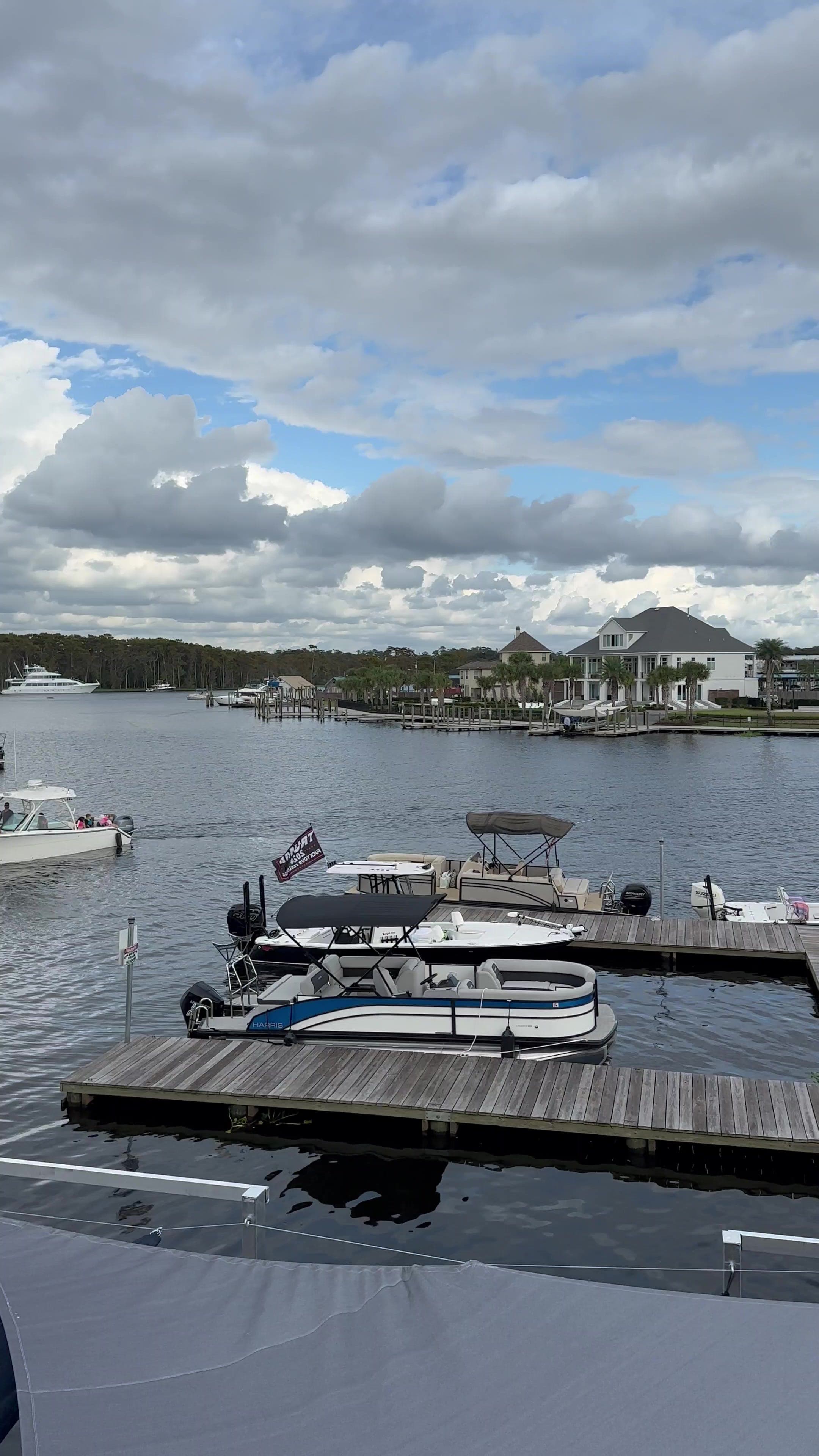Boats moored along the wooden docks of a Tchefuncte River marina, houses on the far bank.